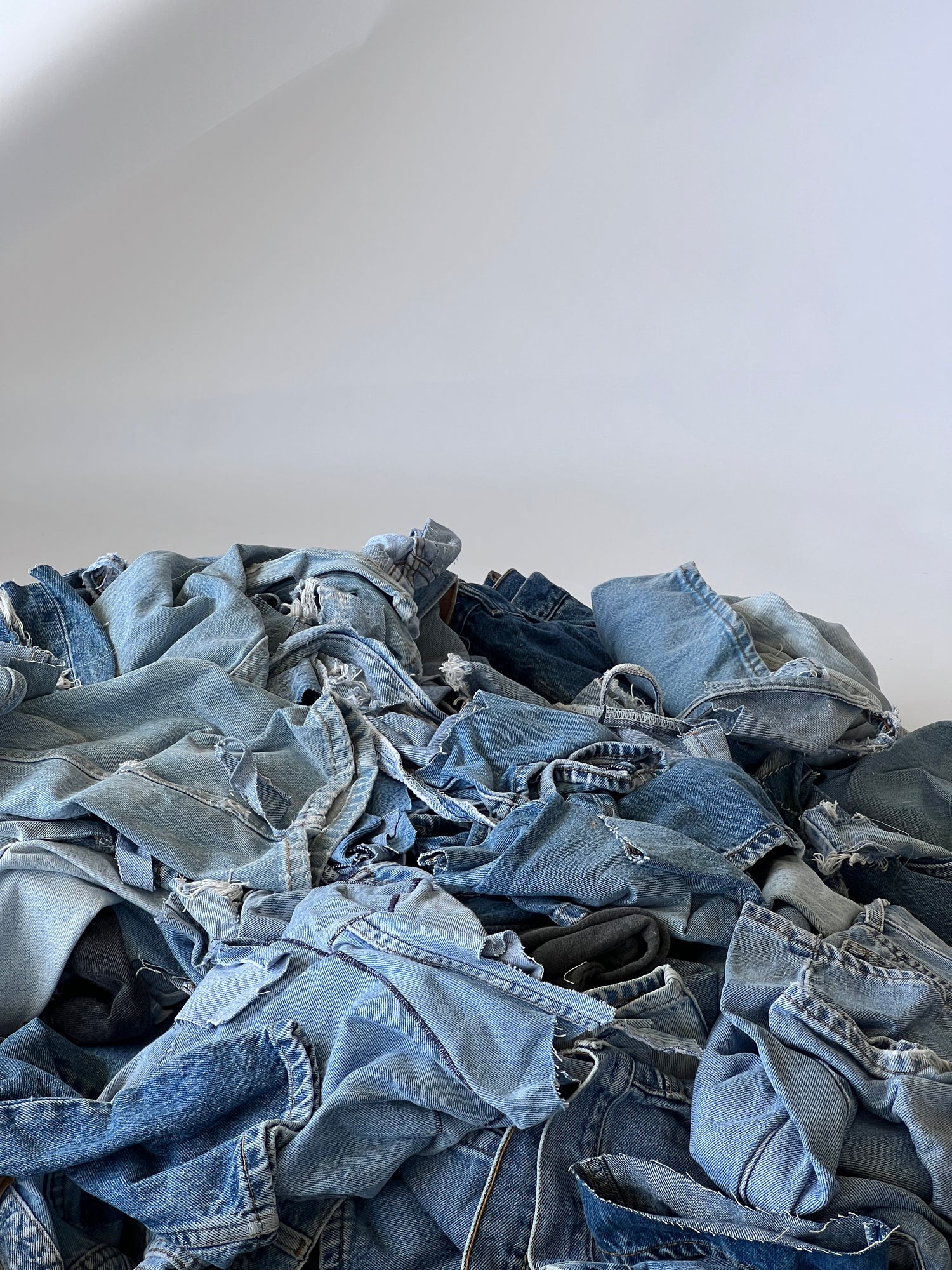 A pile of denim scraps set against a white background.